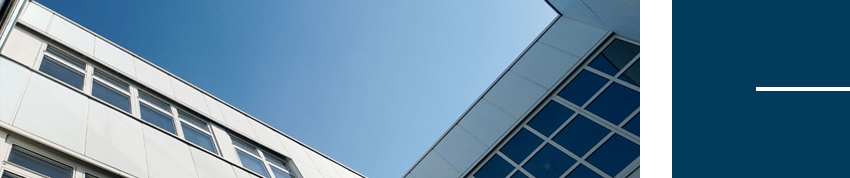 Fassade des Schulgebäudes mit Fensterreihen, von unten gesehen, vor blauem Himmel
