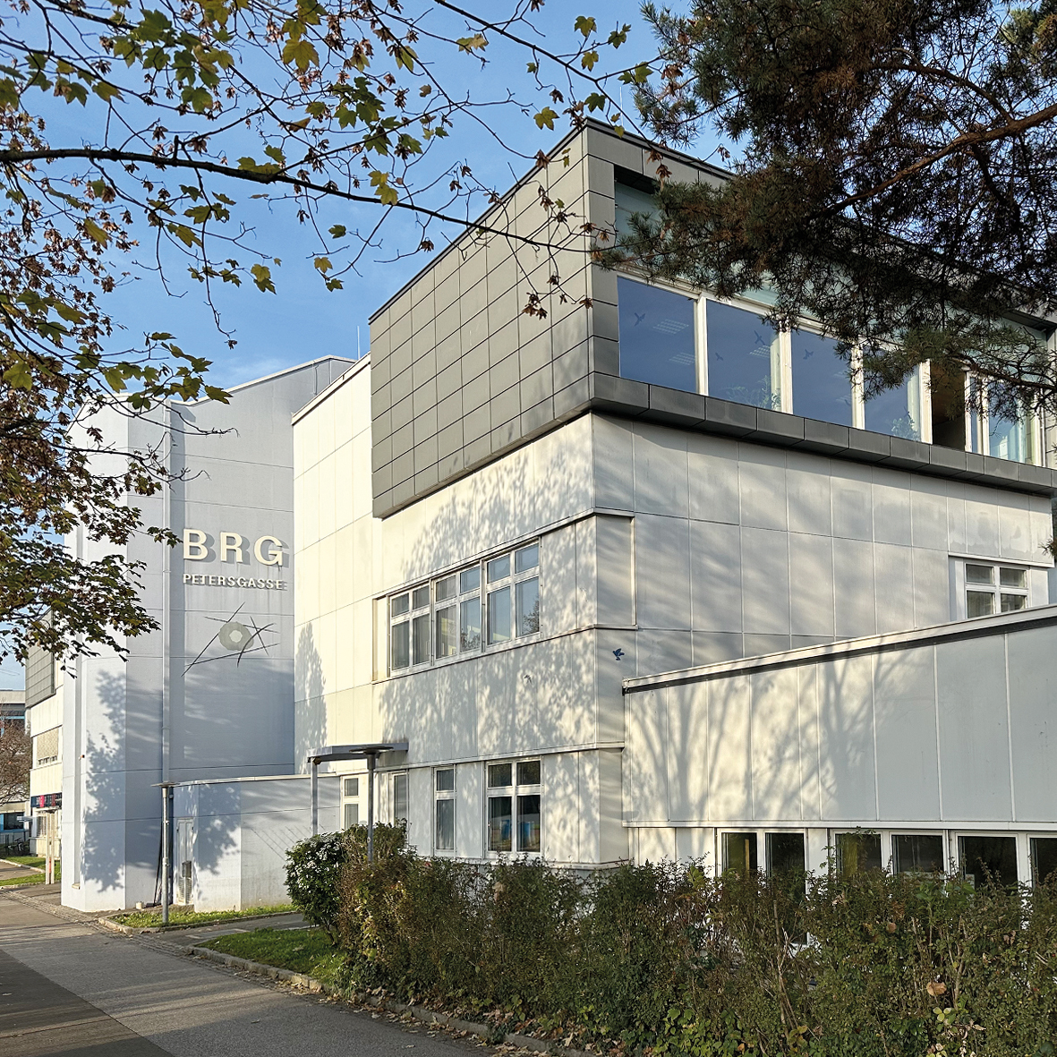 Außenansicht des Schulgebäudes mit dem Schriftzug BRG, davor Bäume